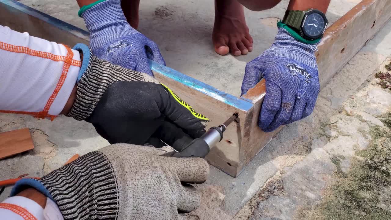 las manos del hombre usan un destornillador para poner manualmente el tornillo en viejas tablas de madera para el marco de la puerta, la restauración
