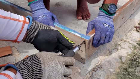 Man-hands-use-screwdriver-to-manually-put-screw-into-old-wooden-boards-for-door-frame,-restoration