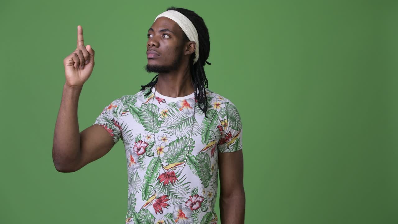 Young handsome African man with dreadlocks against green background