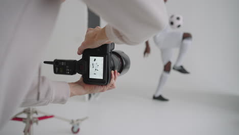 Photographer-takes-professional-photos-of-a-black-football-player-in-the-studio-on-a-white-background