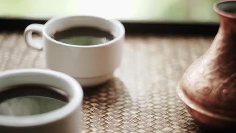 coffee cups and cezve with turkish coffee close to window with view on green trees close up slow motion