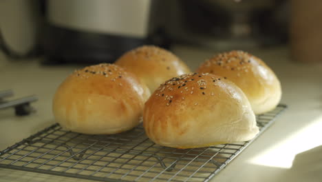 chef cooling some freshly made burger buns topped with multi coloured sesame seeds