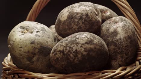 composition of vegetables, rotation of a basket with root vegetables, potatoes, on a black background