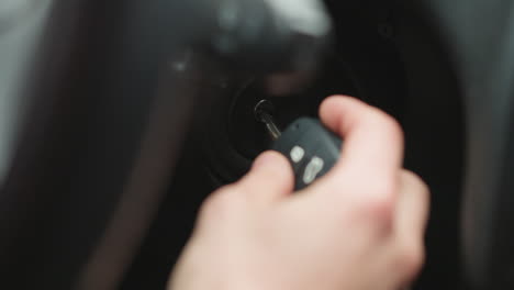 close up of road traveler inserting metal key into ignition starter and turning key inside vehicle cabin focusing on hand movement dashboard detail and winter jacket sleeve before engine start
