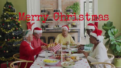 Animation-of-merry-christmas-over-happy-diverse-senior-friends-in-santa-hats-eating-together
