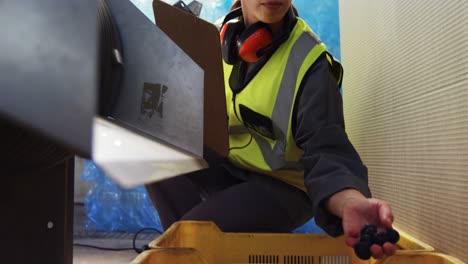 Worker-inspecting-olive-in-machine-in-factory