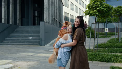 mother and daughter hugging a dog in city