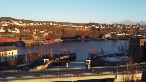 Damfoss-and-Klostergata-bridge-between-Smieoya-and-Klosteroya-islands-in-Skien-Norway---Sunset-evening-aerial-above-water-canal-and-road-FV59