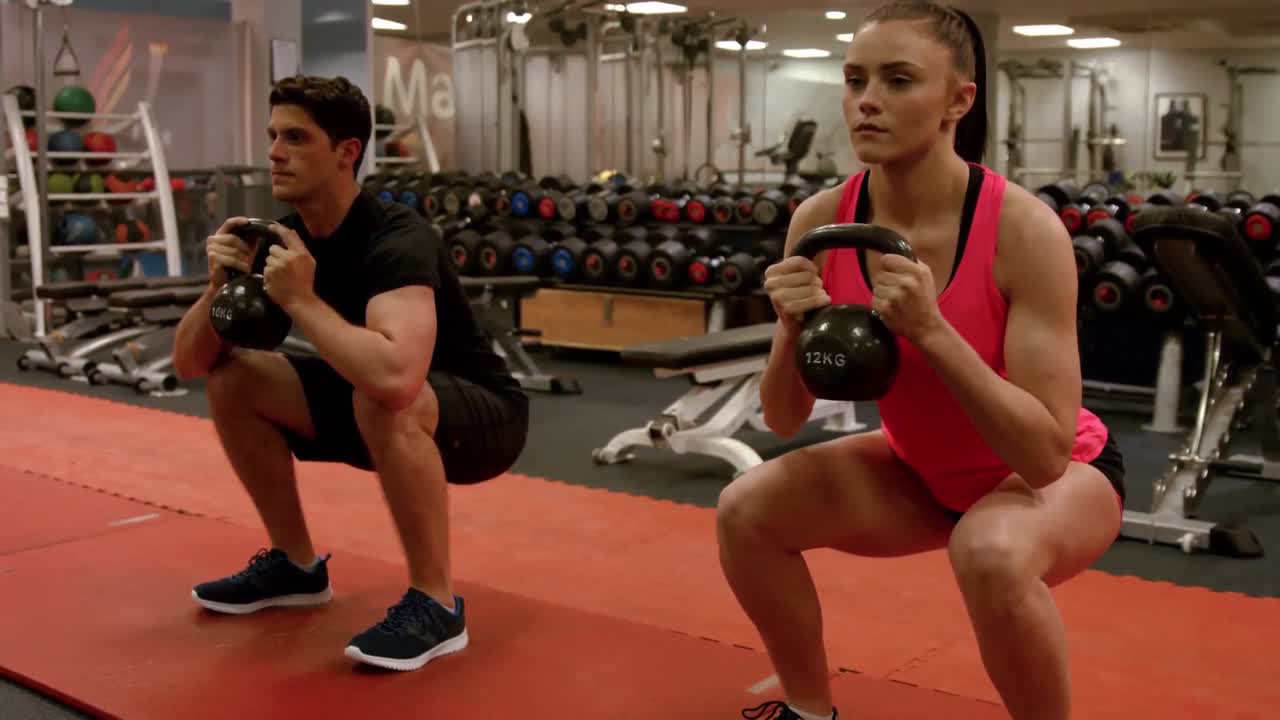 Coppia che esegue squat con pesi in palestra