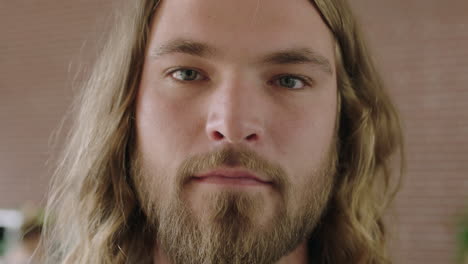 close up portrait of attractive young blonde man looking serious pensive at camera long hair beard