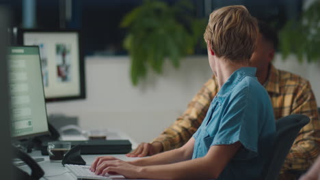 two business colleagues at desks in office working late on project together