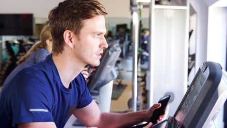 man exercising on cycling machine in gym