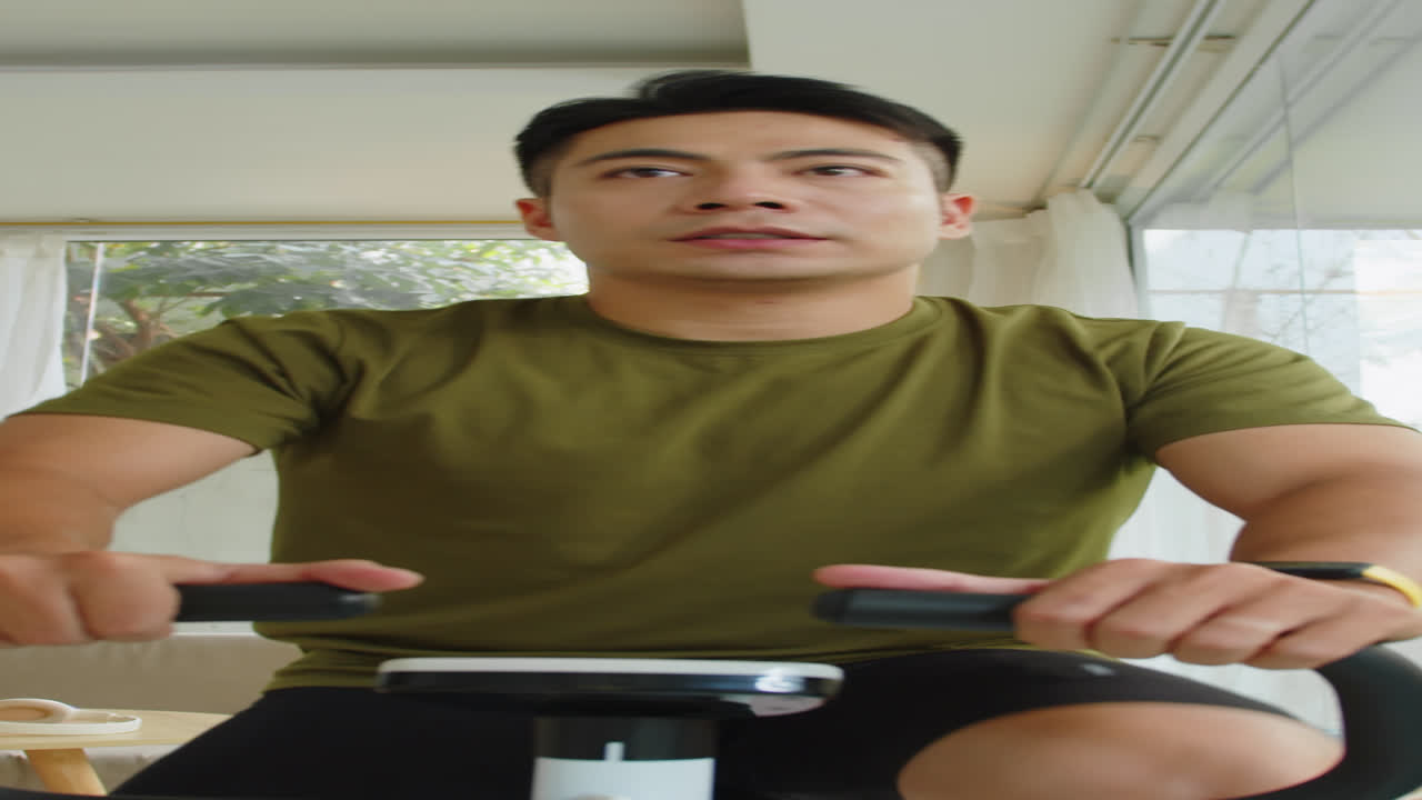 Vertical of Asian Man Checking Pulse on Fitness Band during Bike Exercising