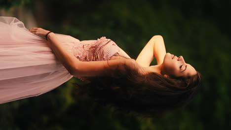 beautiful horizontal shot of a gorgeous young brunette woman dressed in exquisite pink ball gown in a garden during evening time