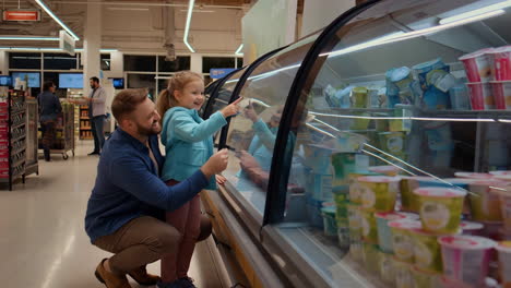 father and daughter shopping for yogurt in a supermarket