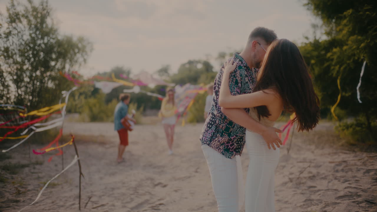 hombre y mujer bailando bachata mientras amigos disfrutan en la playa