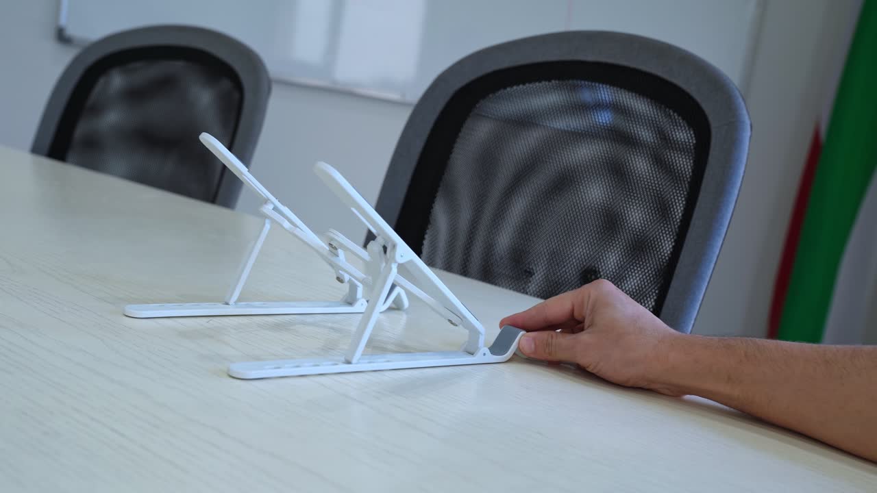 Close-up of hands setting up a foldable laptop stand—ideal for office, tech tutorials, productivity, or workspace organization clips.