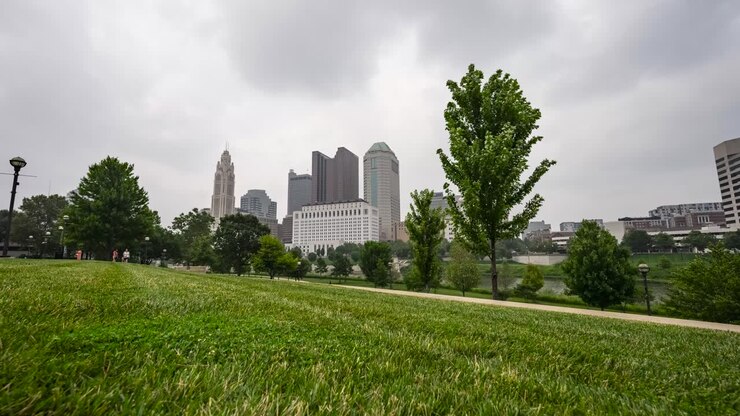 Timelapse de un parque con vistas al horizonte de Columbus, Ohio, en un día brumoso y con humo.
