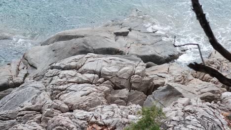 waves gently hit rocks at ao karon, phuket