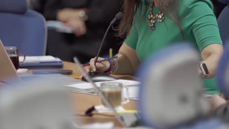 mujer de vestido verde participando con micrófono en una reunión