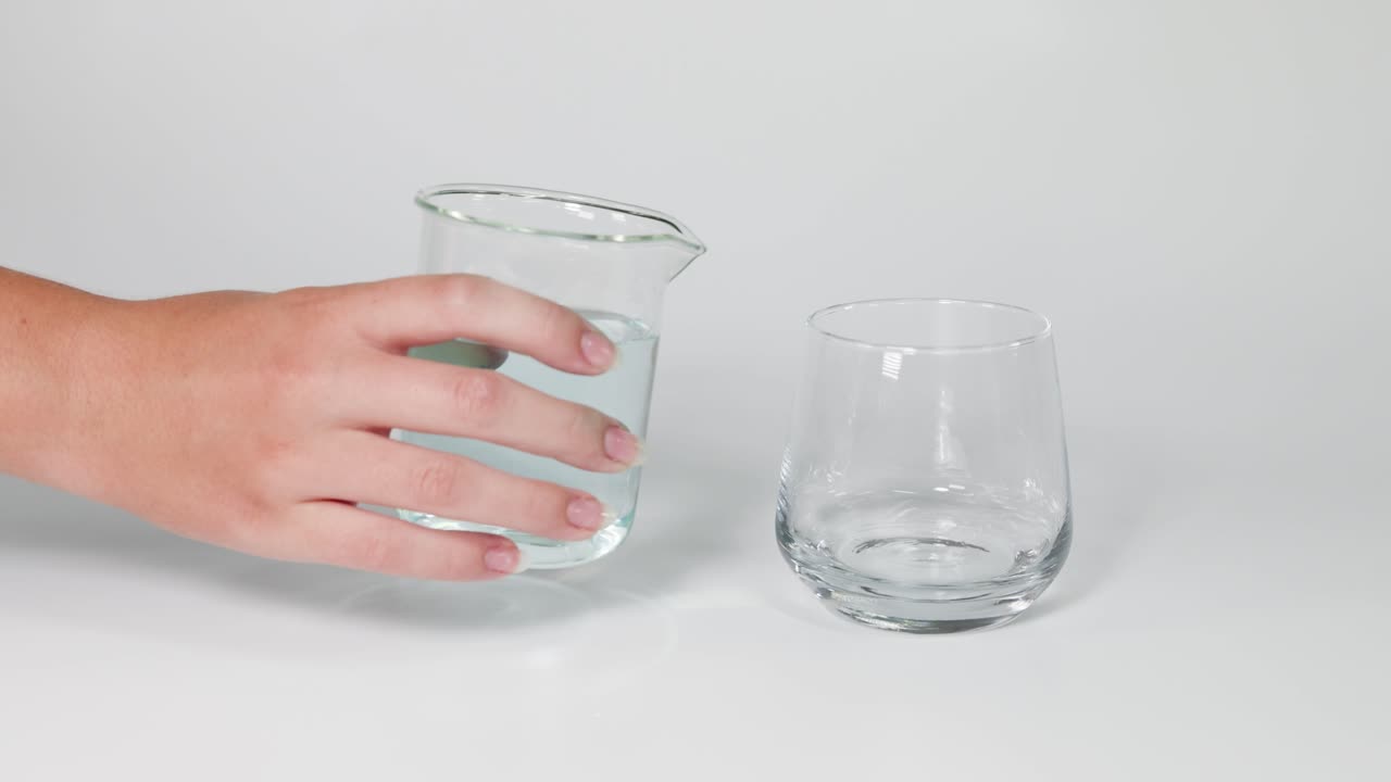 두 개의 투명한 컵 사이에 물을 순차적으로 부어 넣는 것