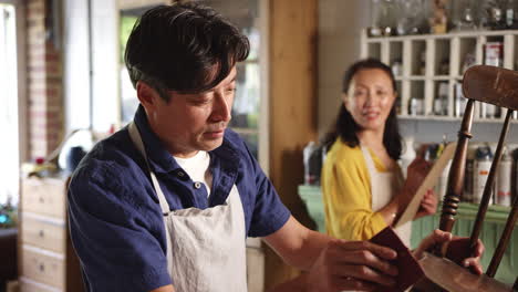 Mature-Asian-couple-restoring-furniture-in-workshop-at-home-together---shot-in-slow-motion