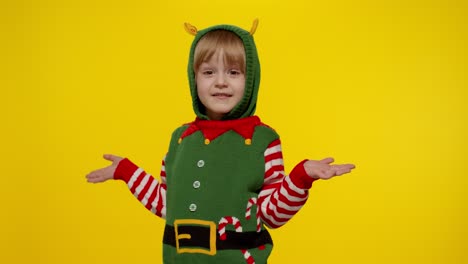 shocked kid girl in christmas elf santa helper costume. child look at camera and ask question what