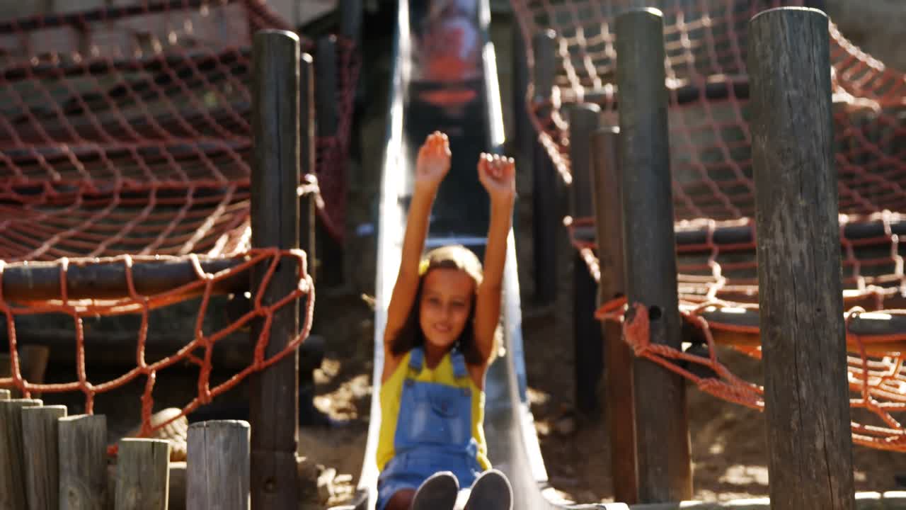 escolar deslizándose en el tobogán en el patio de recreo de la escuela