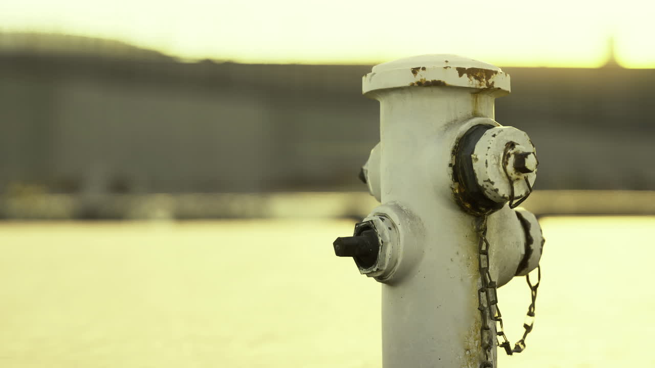 L'idrante si erge fiero sul lungomare mentre il tramonto proietta un bagliore dorato