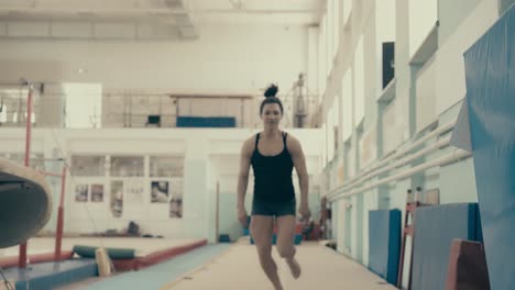 athletic-athletic-girl-in-the-gym-runs-up-and-makes-jump-on-the-mats