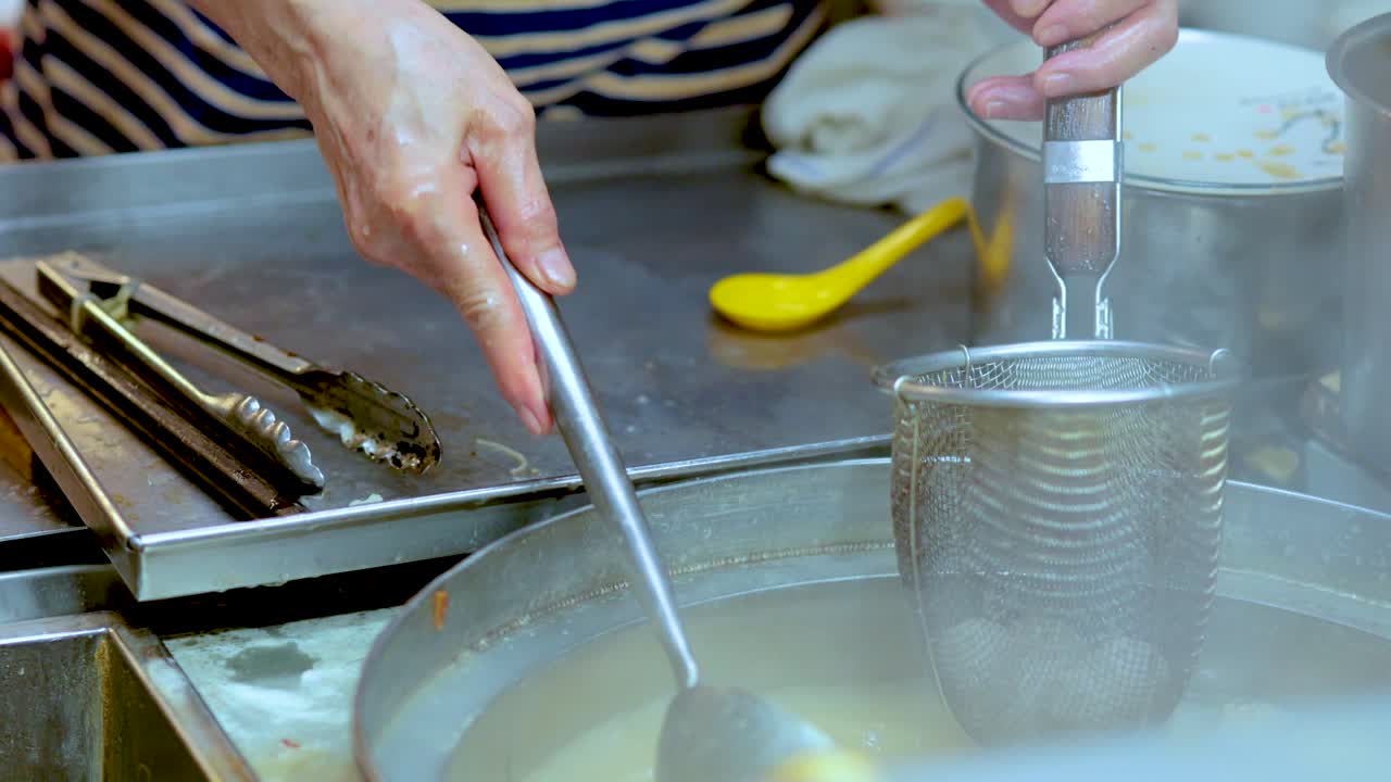 손은 고기으로 누들 수프를 요리하고 있습니다.