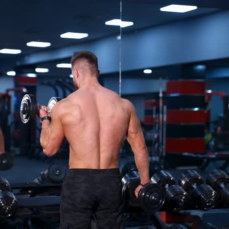strong young man with athletic body doing exercises with dumbbells. fitness, bodybuilding. health care. slow motion