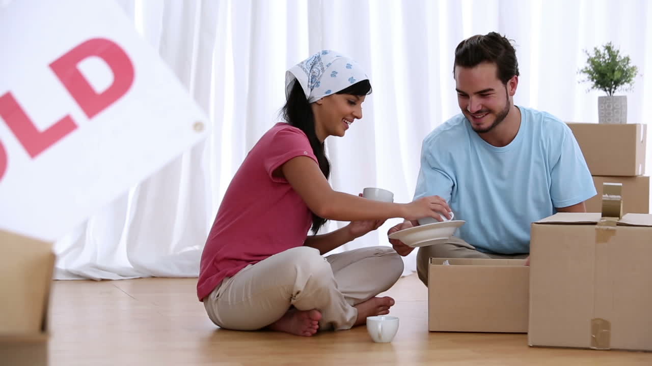 una pareja desempaquetando cajas de mudanzas.