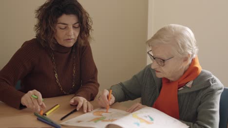 caregiver and senior woman coloring a draw in a geriatric