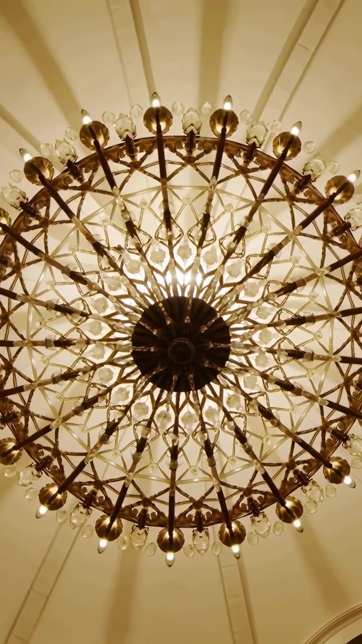 Vertical video: Tilting camera capturing chandelier in formal foyer to show crystal drops