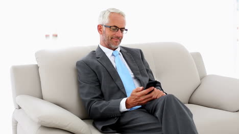 hombre de negocios enviando un texto en el sofá