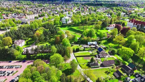 vibrant green countryside with scattered houses transitions into a more densely packed city in the background, offering a contrast of rural and urban life from above.