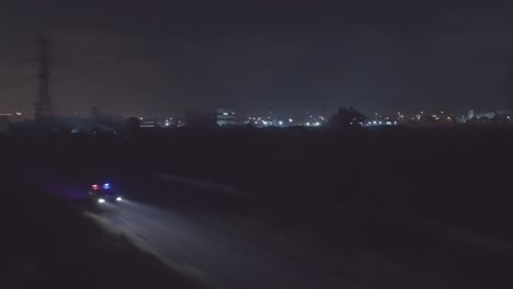 night aerial footage of a police car driving down a dark urban area