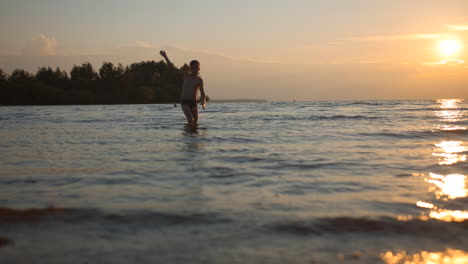 child playing in water at sunset