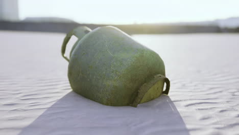 Green container rests on sandy terrain under bright sunlight