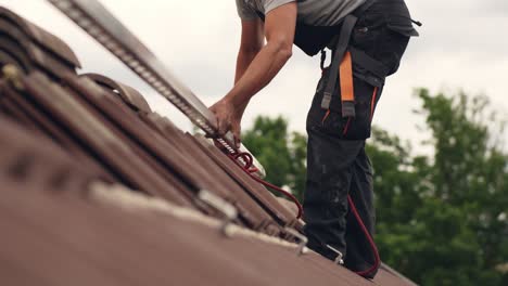 ground level view of roofer worker adding mounts for solar panel home, day