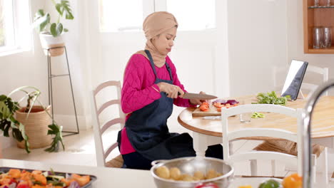 biracial woman in hijab washing food at table at home with copy space, slow motion