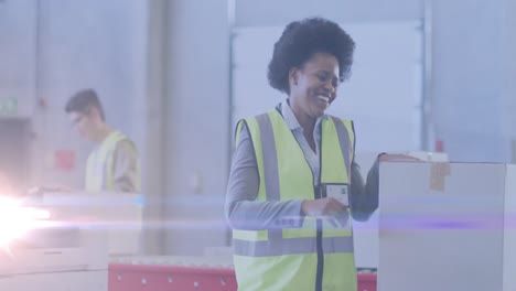Animation-of-glowing-light-over-african-american-woman-working-in-warehouse