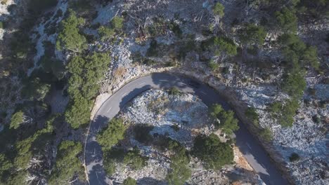4k top down shot of a car driving through a curve in mallorca in the national reserve serra de tramuntana