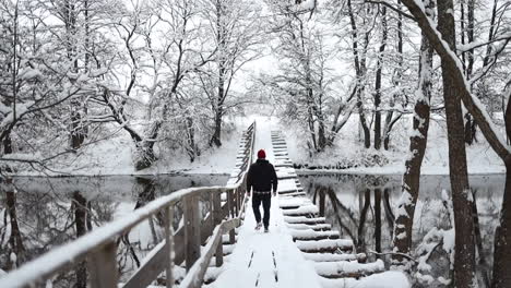 el hombre está caminando sobre un puente cubierto de nieve en un paisaje invernal, un clima frío y refrescante