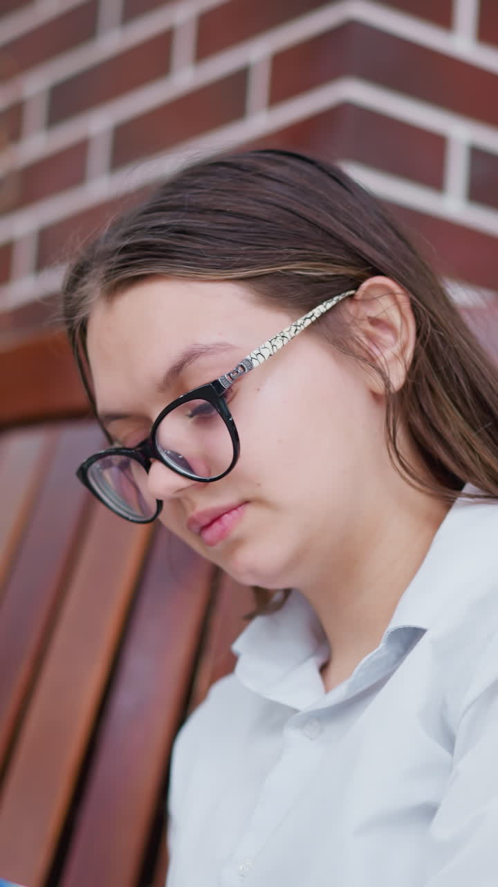 joven con gafas se sienta en un banco de madera en un centro comercial moderno, profundamente absorta en el libro, las luces bokeh en el fondo crean una atmósfera cálida, enfatizando el enfoque y la curiosidad intelectual