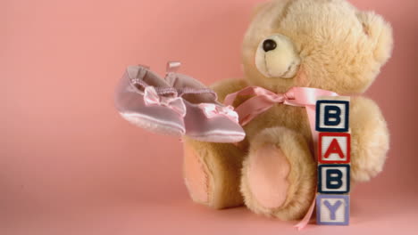 baby shoes falling next to a teddy bear and baby blocks