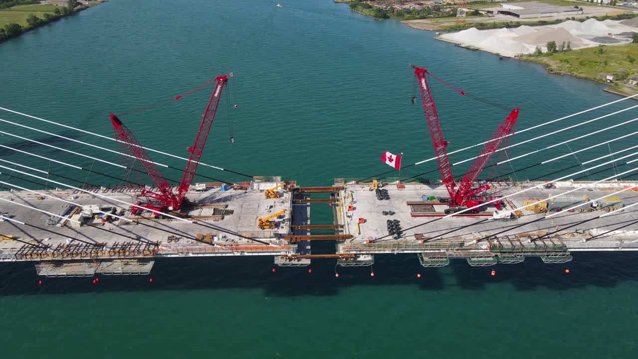 Progress of Gordie Howe international bridge construction with lattice boom crawler cranes