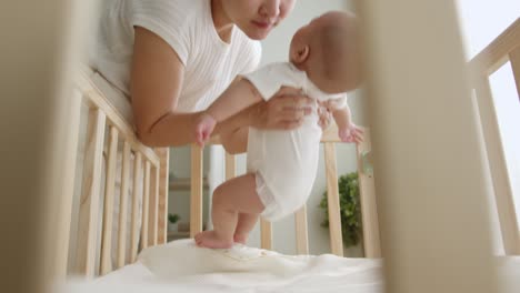 young asian mother carry up her newborn baby from crib