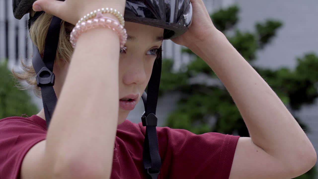 Young boy fits bike helmet on head outside before a ride, close up